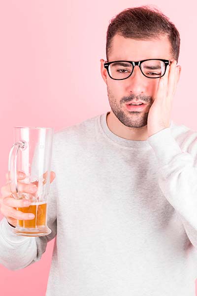 мужчина с кружкой пива в руке мучается с похмелья