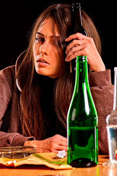 женщина сидит за столом с бутылкой алкоголя