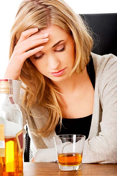 расстроенная женщина со стаканом алкоголя
