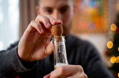 Мужчина открывает бутылку шампанского