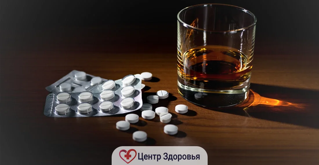 Белые таблетки россыпью рядом с бокалом виски