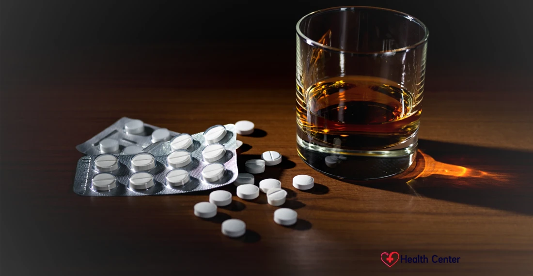 Белые таблетки россыпью рядом с бокалом виски